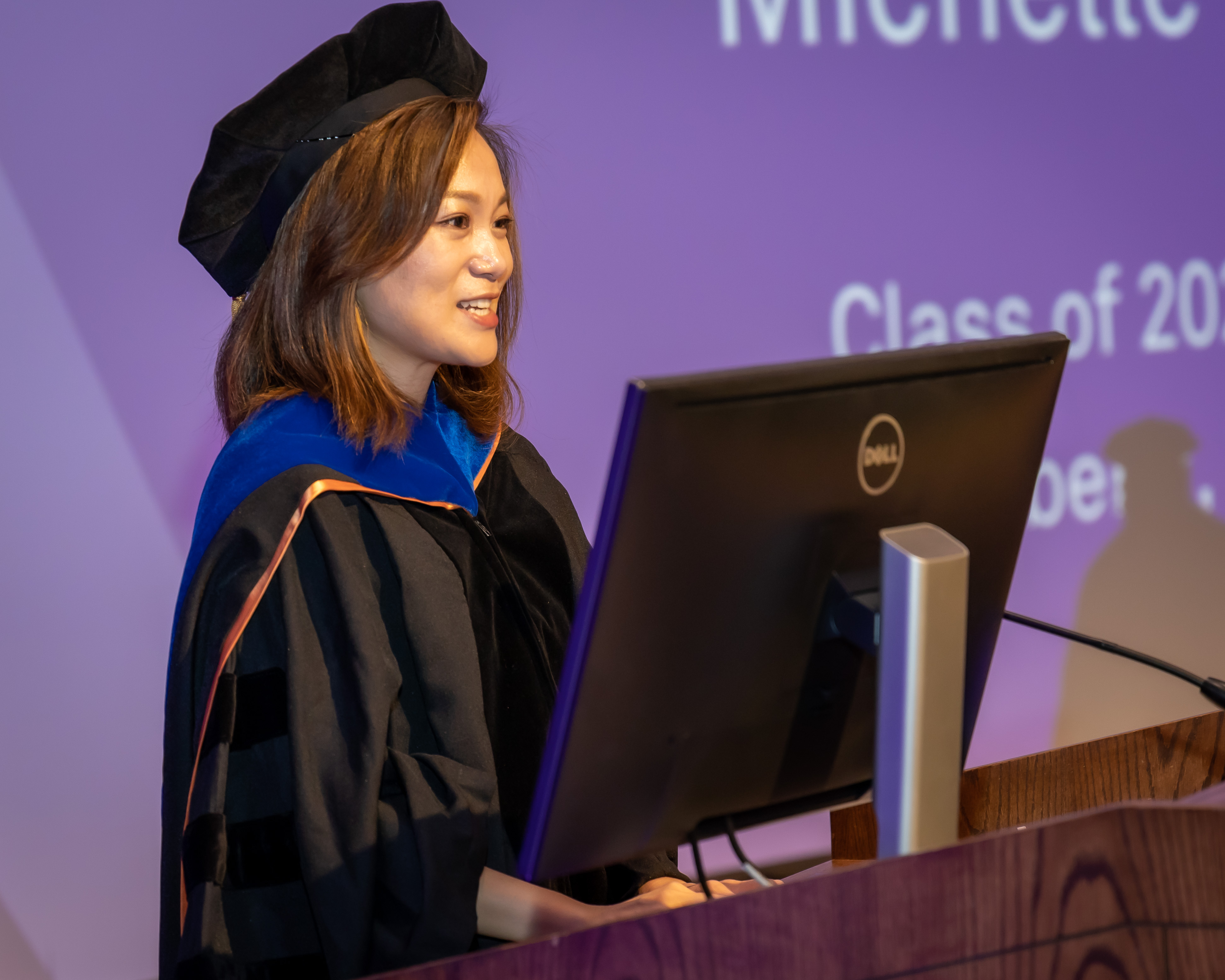 Dr. Yin speaking at graduation ceremony in academic regalia